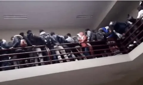 Bolivian University students lean against the railing on the fourth floor balcony moments before collapse.